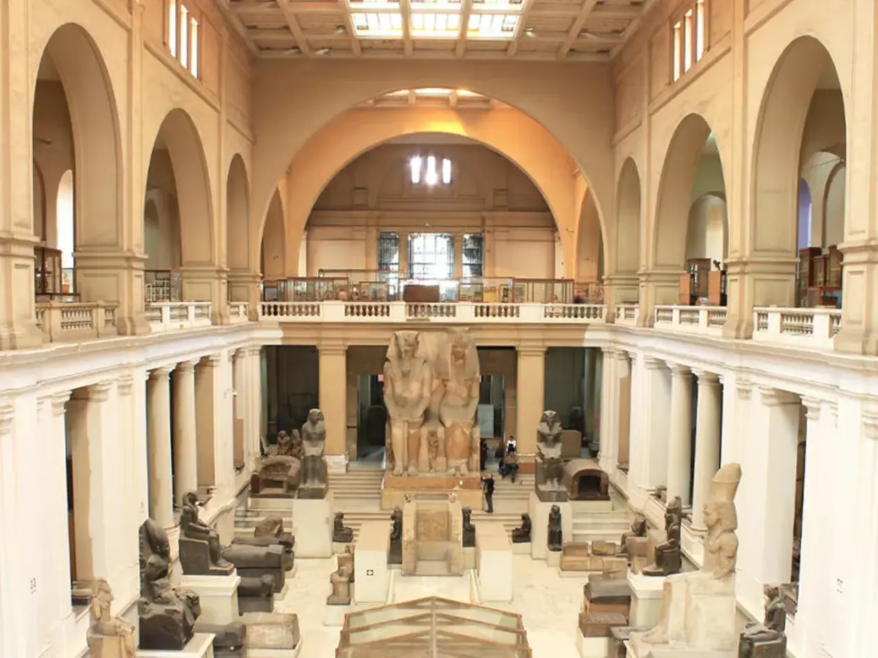 Wielka sala w muzeum w Kairze, pełna starożytnych posągów i artefaktów. Monumentalne rzeźby faraonów dominują w centrum.