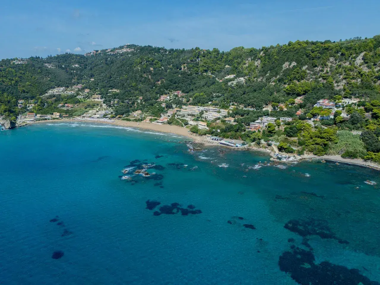 Widok na zatokę z piaszczystą plażą i zielonymi wzgórzami. To malownicza mysia wyspa Korfu, idealna na wakacje.