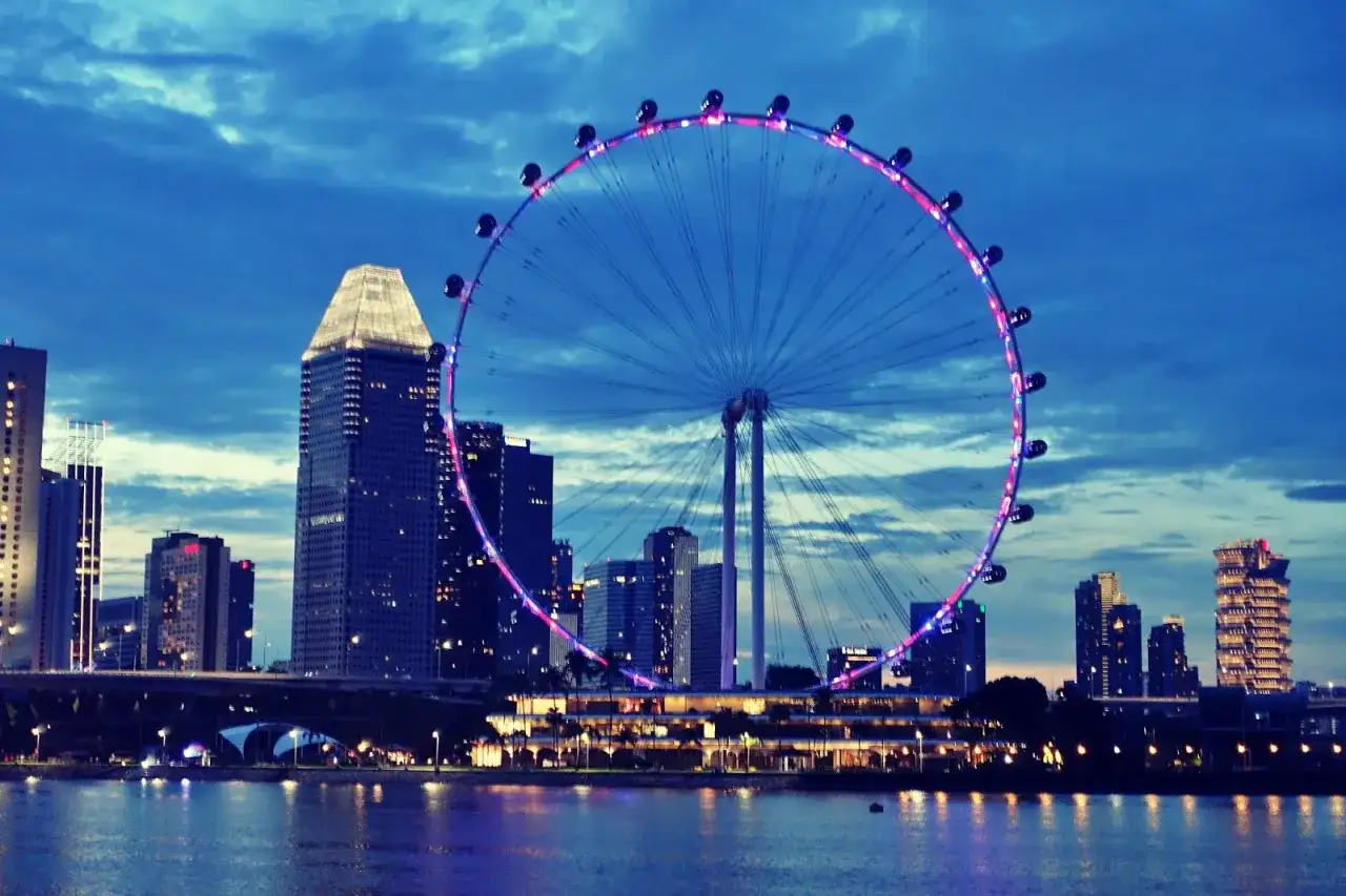 Wieczorny widok na Singapur z diabelskim młynem i drapaczami chmur. Marzenie o podróży, wiza do Singapuru czeka!