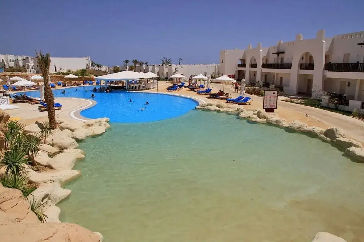 Basen w Hilton Marsa Alam Nubian Resort. Opinie gości potwierdzają piękno tego miejsca z białymi budynkami i palmami.