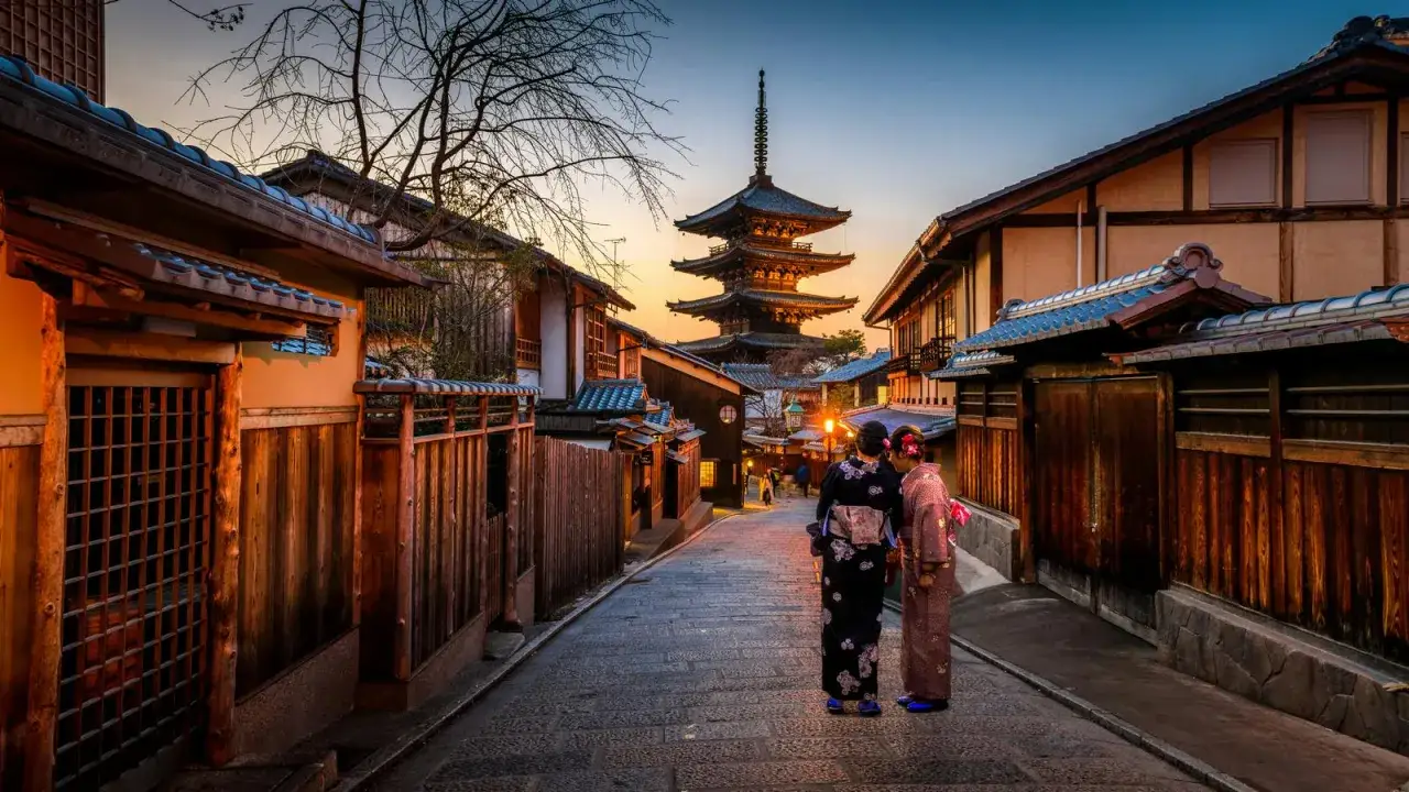 Dwie kobiety w kimonach stoją na brukowanej uliczce w Kioto, podziwiając pagodę. Czy do Japonii potrzebna jest wiza?