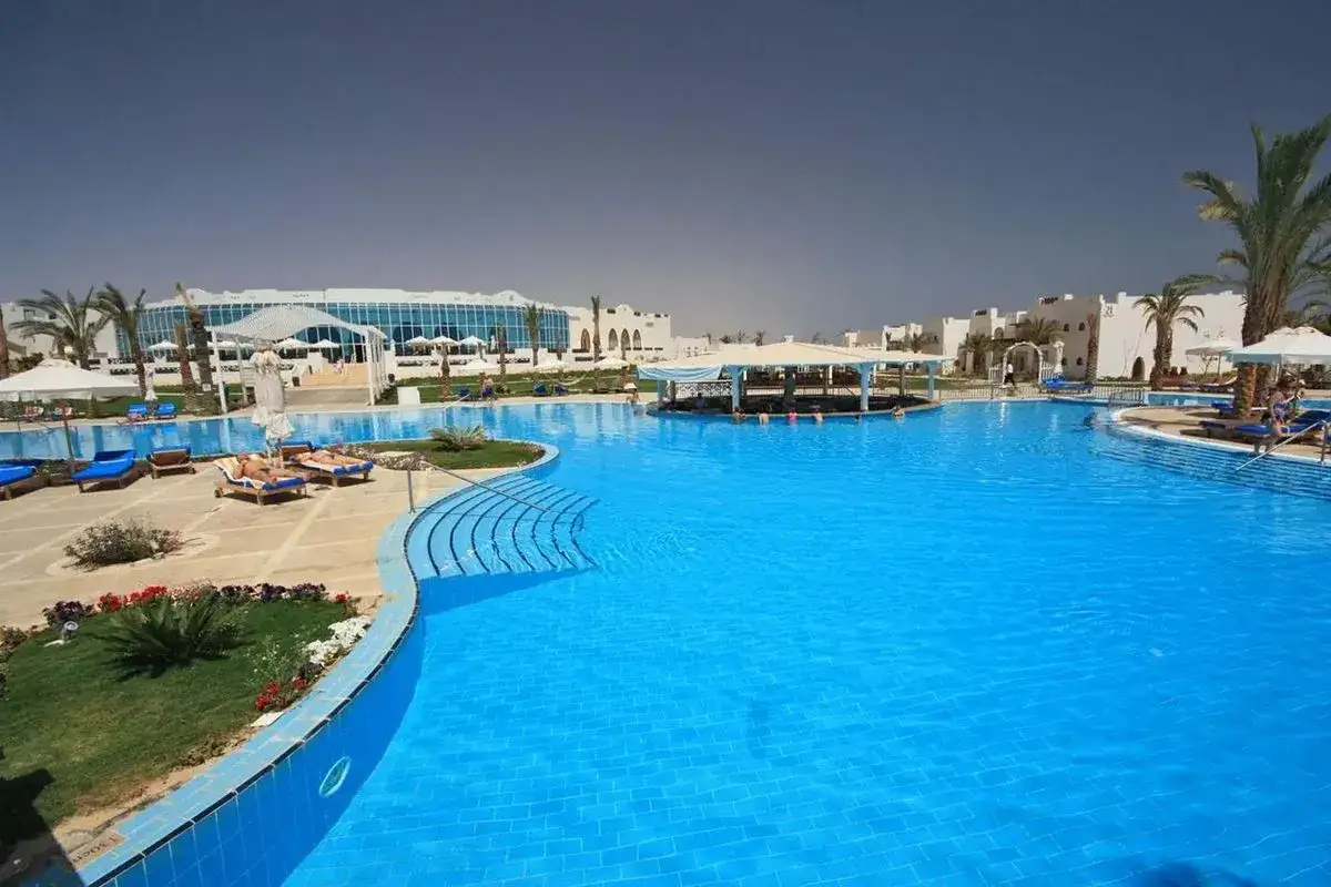 Basen z barem i leżakami w Hilton Marsa Alam Nubian Resort. Wiele osób relaksuje się w wodzie.