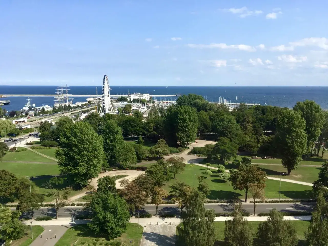 Widok na park, morze i port w Gdyni. W oddali koło widokowe i żaglowce. Warto sprawdzić mercure gdynia centrum opinie przed podróżą.