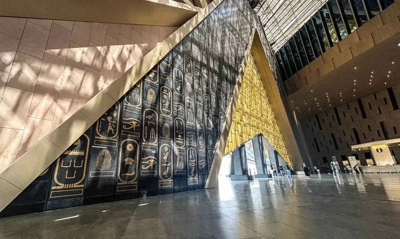 Wnętrze nowego muzeum w Kairze z imponującą ścianą ozdobioną hieroglifami i złotymi detalami.