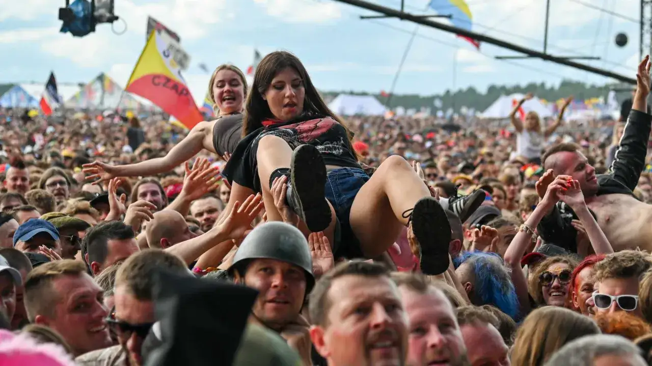 Dziewczyna na rękach tłumu na festiwalu Woodstock. Radosna atmosfera, muzyka i energia.