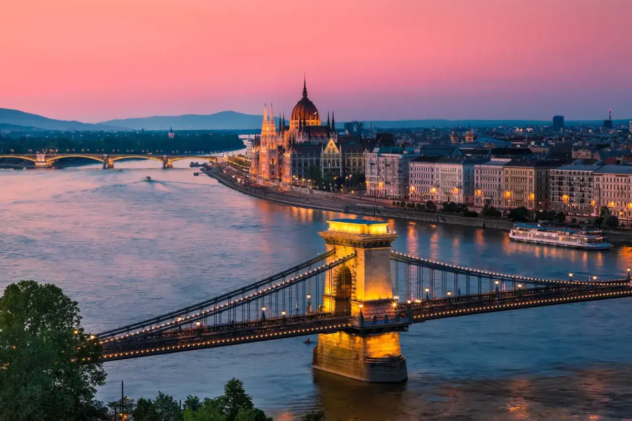 Budapeszt o zachodzie słońca, z oświetlonym Mostem Łańcuchowym i Parlamentem. Idealne miejsce na tanie loty na weekend.