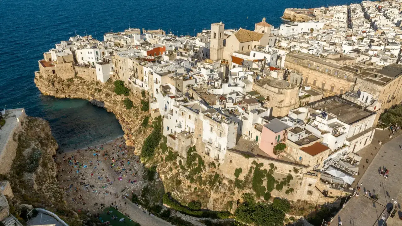Bari, październik. Słoneczna pogoda zachęca do plażowania w Polignano a Mare, malowniczym miasteczku na klifie.