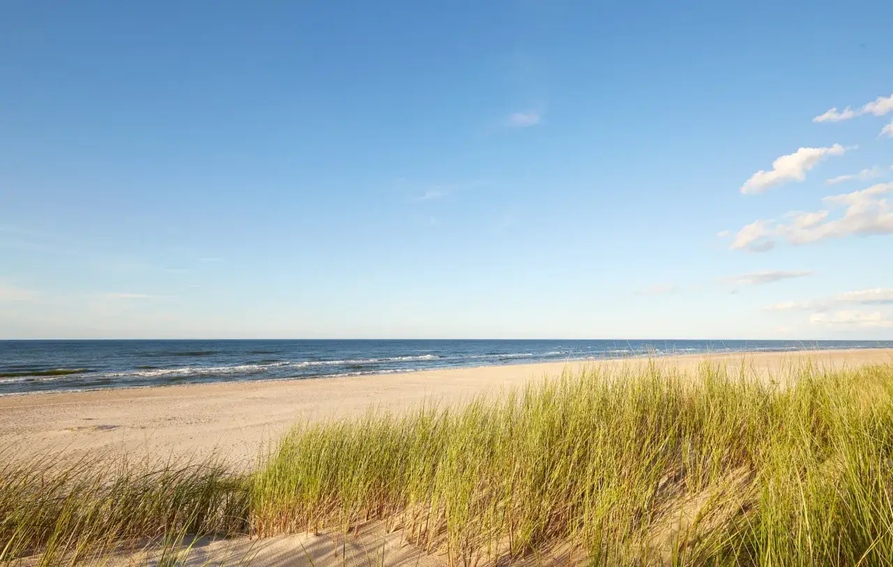 Słajszewo plaża: złocisty piasek, szum fal i trawy na wydmach pod błękitnym niebem. Idealne miejsce na relaks.