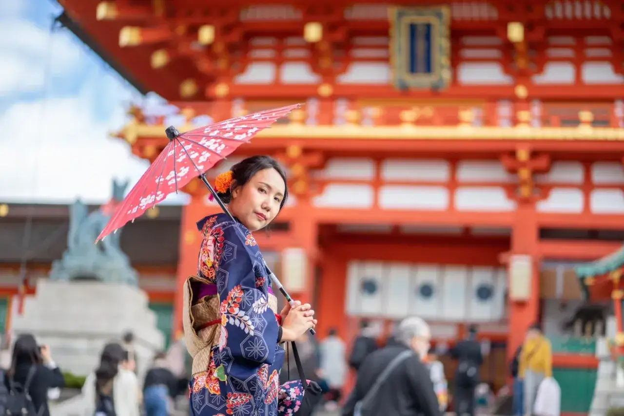 Kobieta w kimonie z parasolką przed japońską świątynią. Czy do Japonii potrzebna jest wiza?