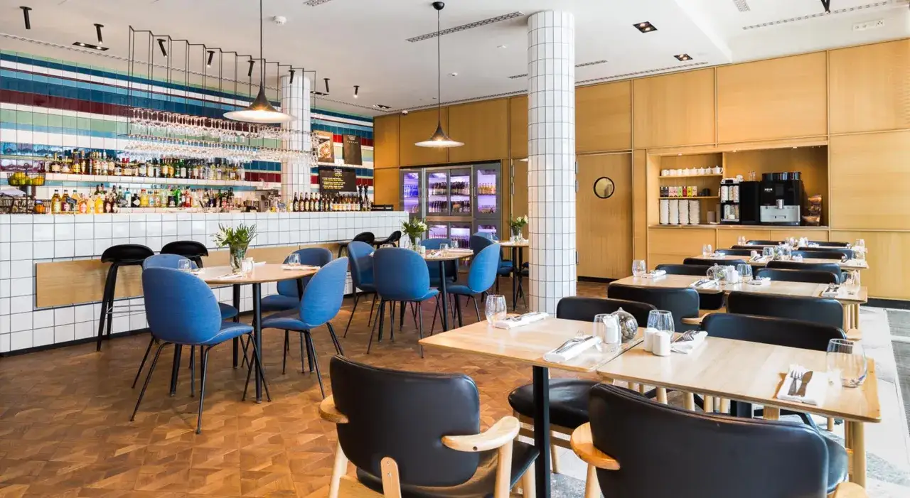 Nowoczesna restauracja hotelu Puro we Wrocławiu z niebieskimi krzesłami i drewnianymi elementami.