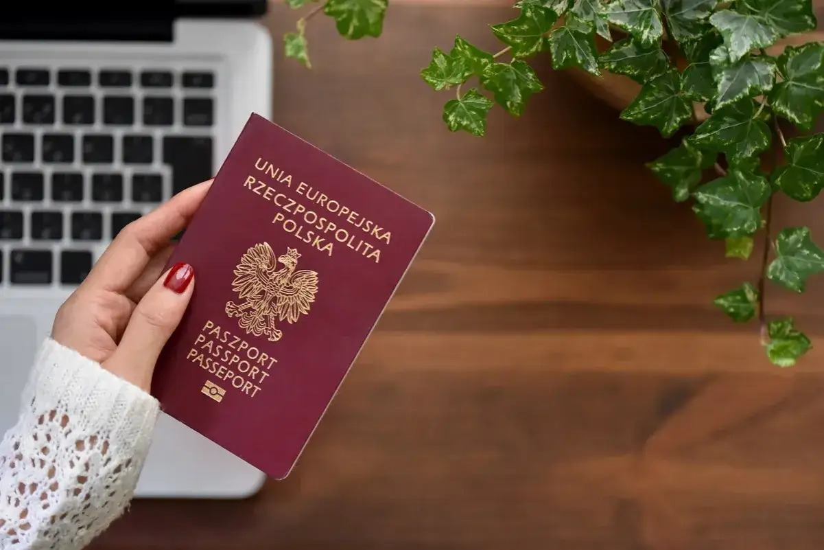 Dłoń trzyma polski paszport. Planujesz podróż i zastanawiasz się, jaki jest koszt paszportu?