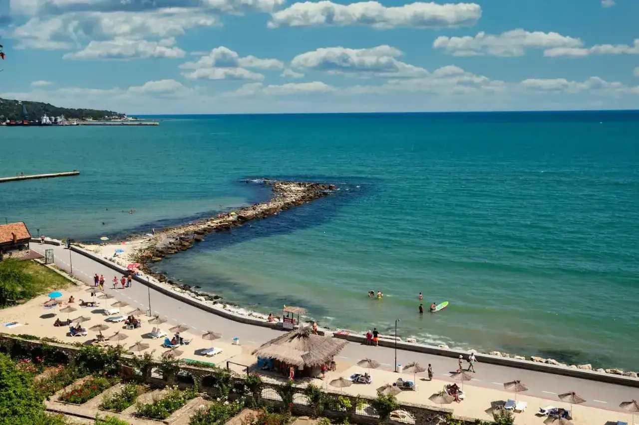 Piękna pogoda w Bułgarii w maju. Słoneczny dzień nad Morzem Czarnym, plaża z leżakami i parasolami, ludzie kąpią się i spacerują.