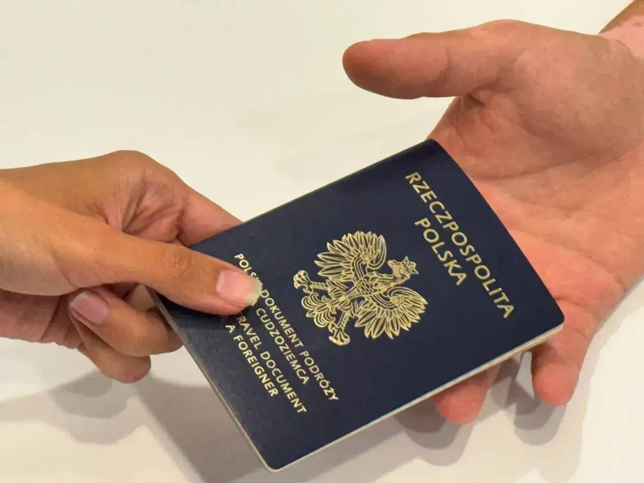 Dłoń przekazuje paszport tymczasowy. Zastanawiasz się, ile kosztuje paszport tymczasowy?