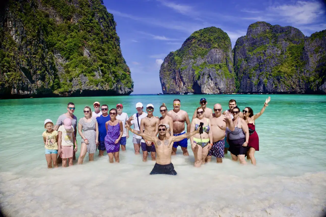 Grupa ludzi cieszy się słońcem i turkusową wodą na plaży Maya Bay.