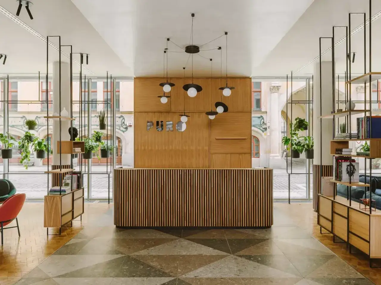 Nowoczesne wnętrze hotelu Puro Wrocław z drewnianą ladą recepcyjną, wiszącymi lampami i mnóstwem zieleni.