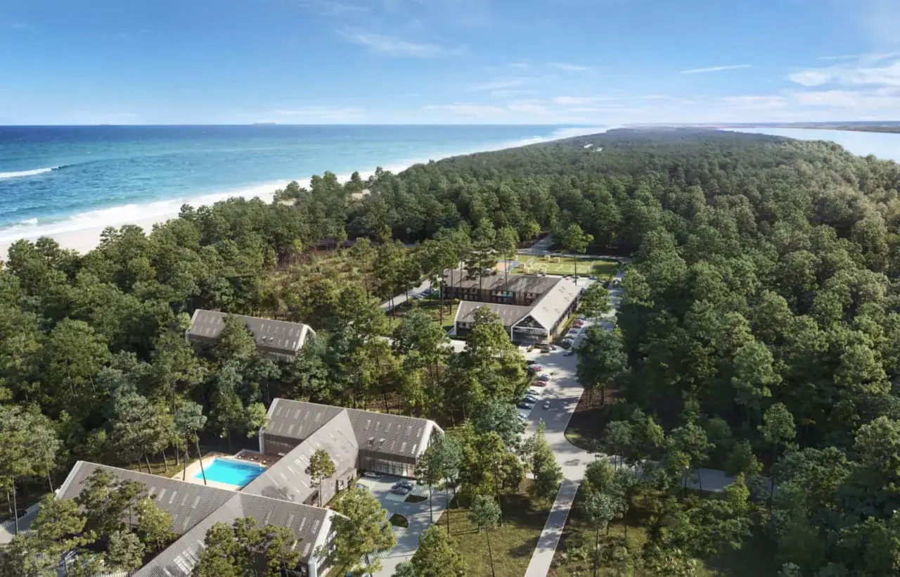 Widok z lotu ptaka na kompleks budynków otoczony lasem, z basenem i plażą w tle. Idealne miejsce na wypoczynek, jak sugerują pozytywne saltic resort & spa łeba opinie.