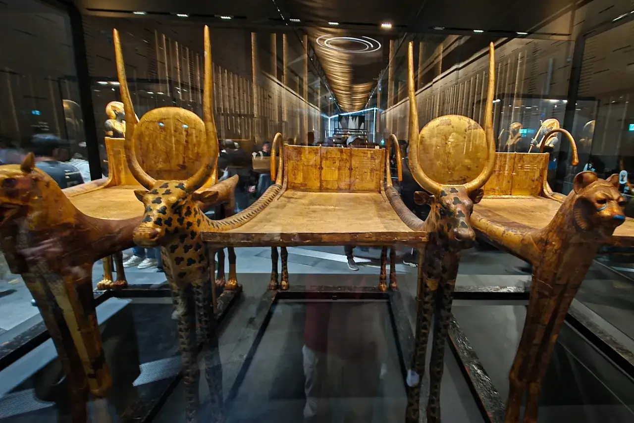 Złote tronki z motywami zwierzęcymi, ozdobione tarczami i rogami, w muzeum egipskim.
