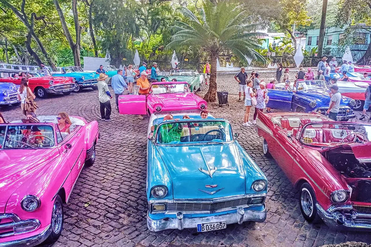 Kolorowe, klasyczne samochody na ulicach wyspy kuba. Ludzie podziwiają zabytkowe auta, tworząc atmosferę retro.