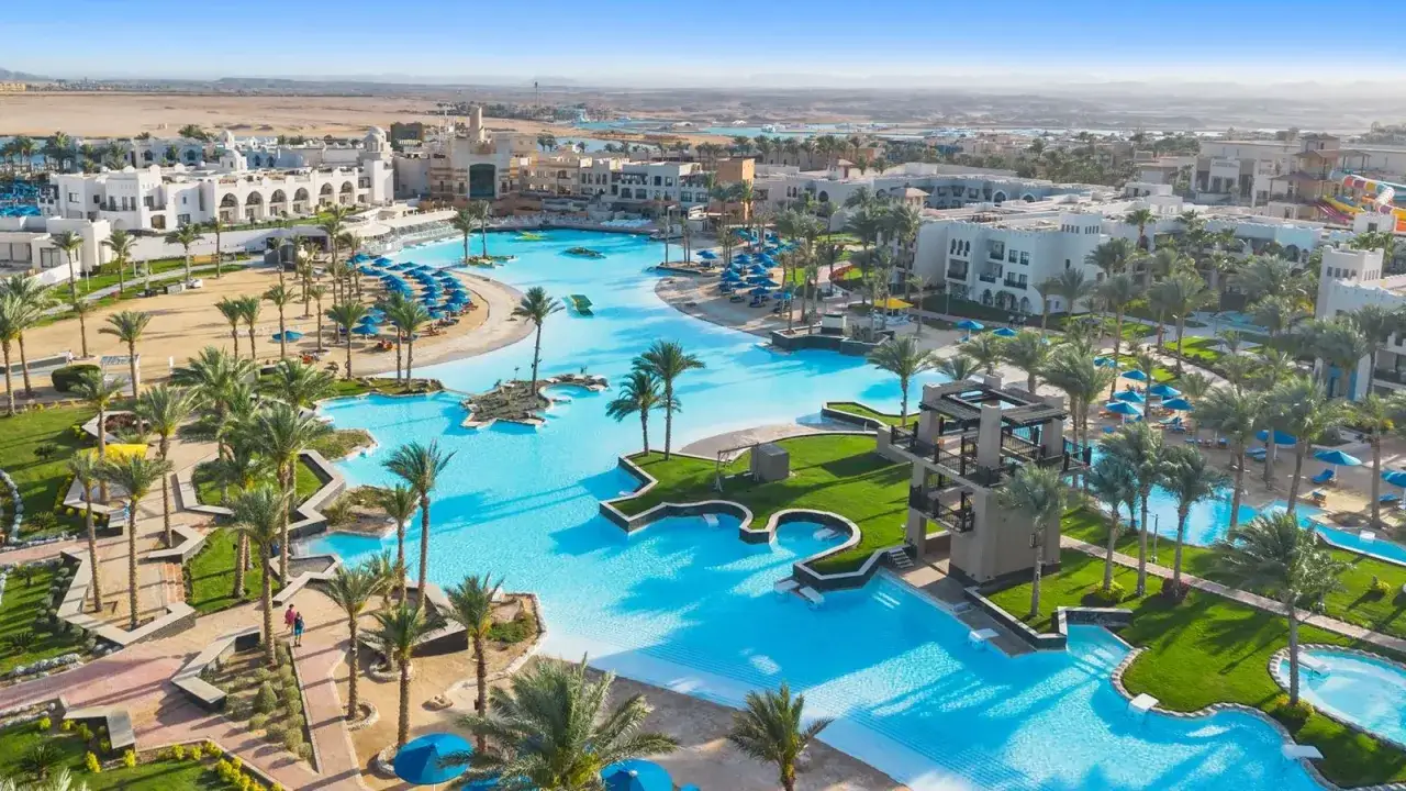 Piękny kompleks basenów i budynków hotelowych z palmami. Idealne miejsce na wakacje, zgodnie z pozytywnymi pickalbatros oasis port ghalib opinie.