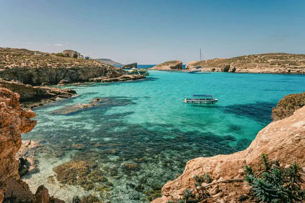 Turkusowa zatoka z łodziami, skaliste wybrzeże. Czy Malta, czy warto? Tak, warto!