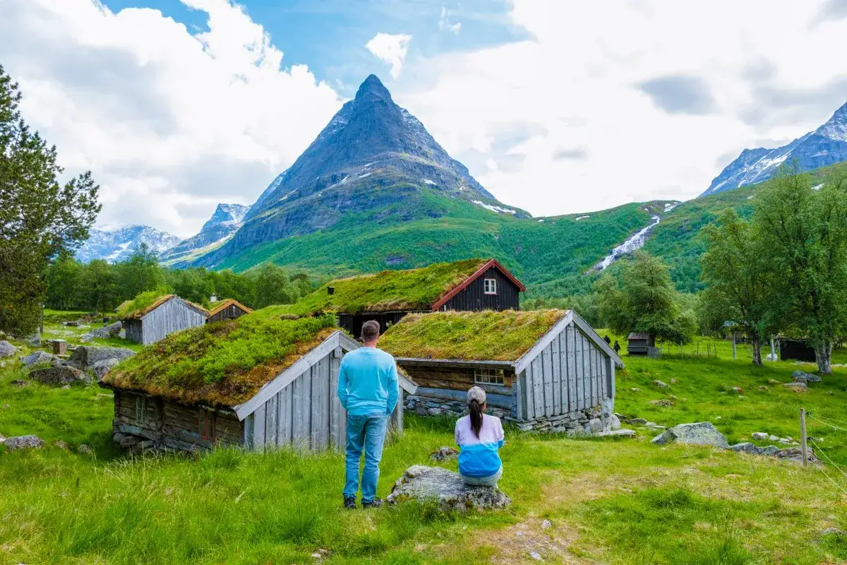 Para zwiedzająca tradycyjne norweskie chatki z zielonymi dachami. Czy do Norwegii potrzebny jest paszport? To pytanie nie dotyczy tej malowniczej scenerii.