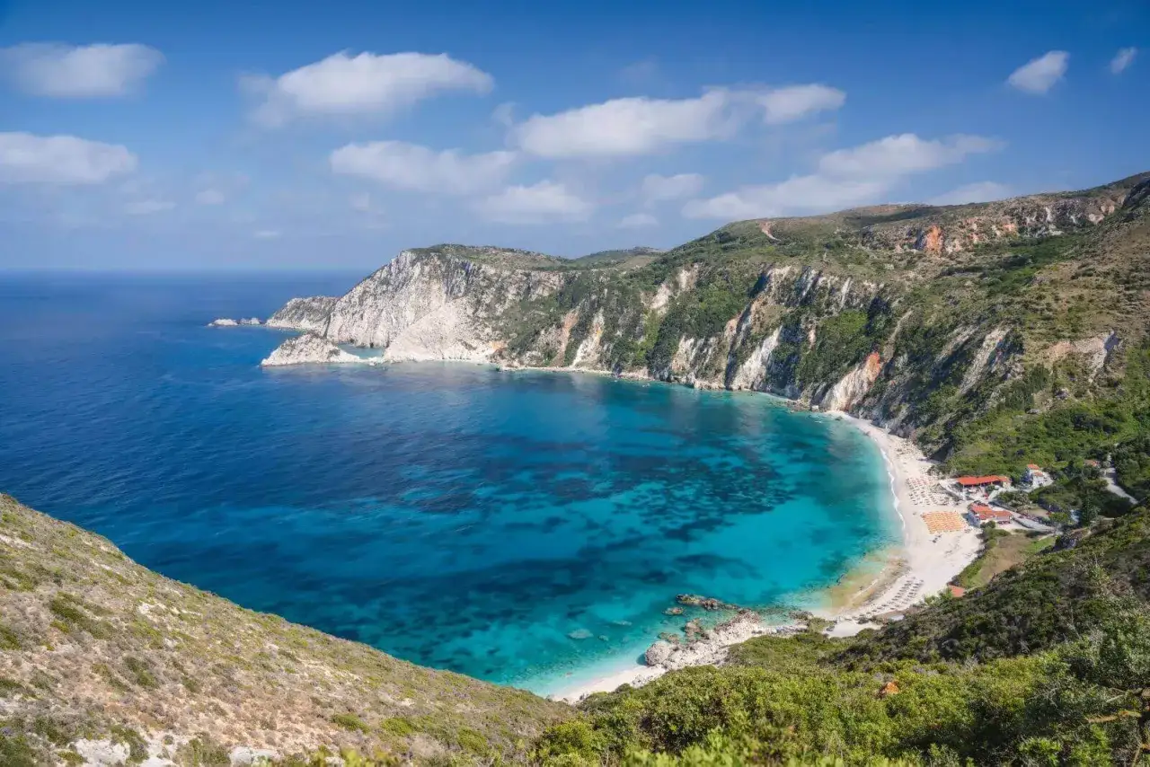 Malownicza zatoka z turkusową wodą i piaszczystą plażą, otoczona klifami. To urokliwa wyspa Eptanisa, idealna na wakacje.