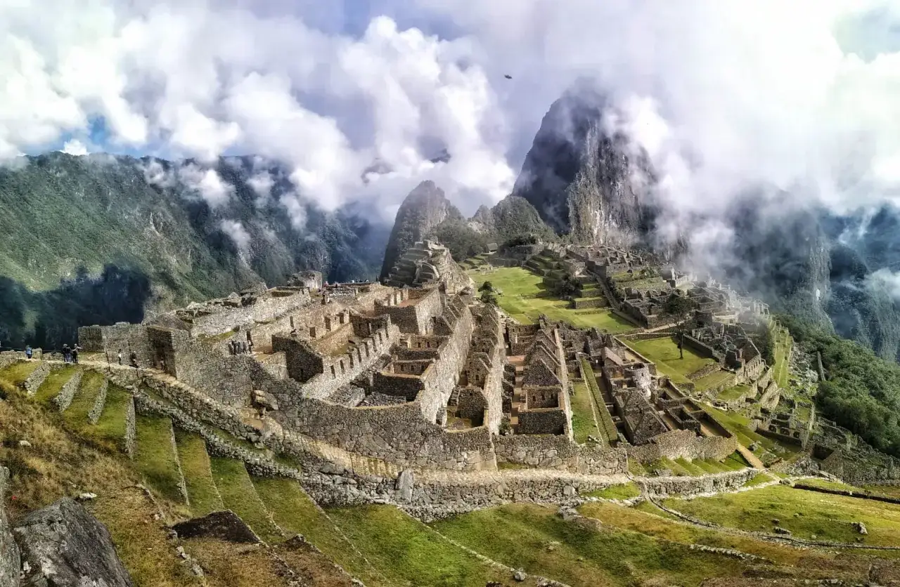 Niesamowita wycieczka do Machu Picchu. Ruiny Inków w chmurach, otoczone zielonymi tarasami i górami.