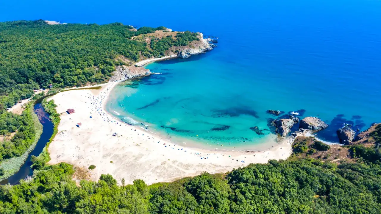 Malownicza zatoka z piaszczystą plażą, turkusową wodą i zielonymi wzgórzami. Idealne bułgarskie plaże dla każdego.