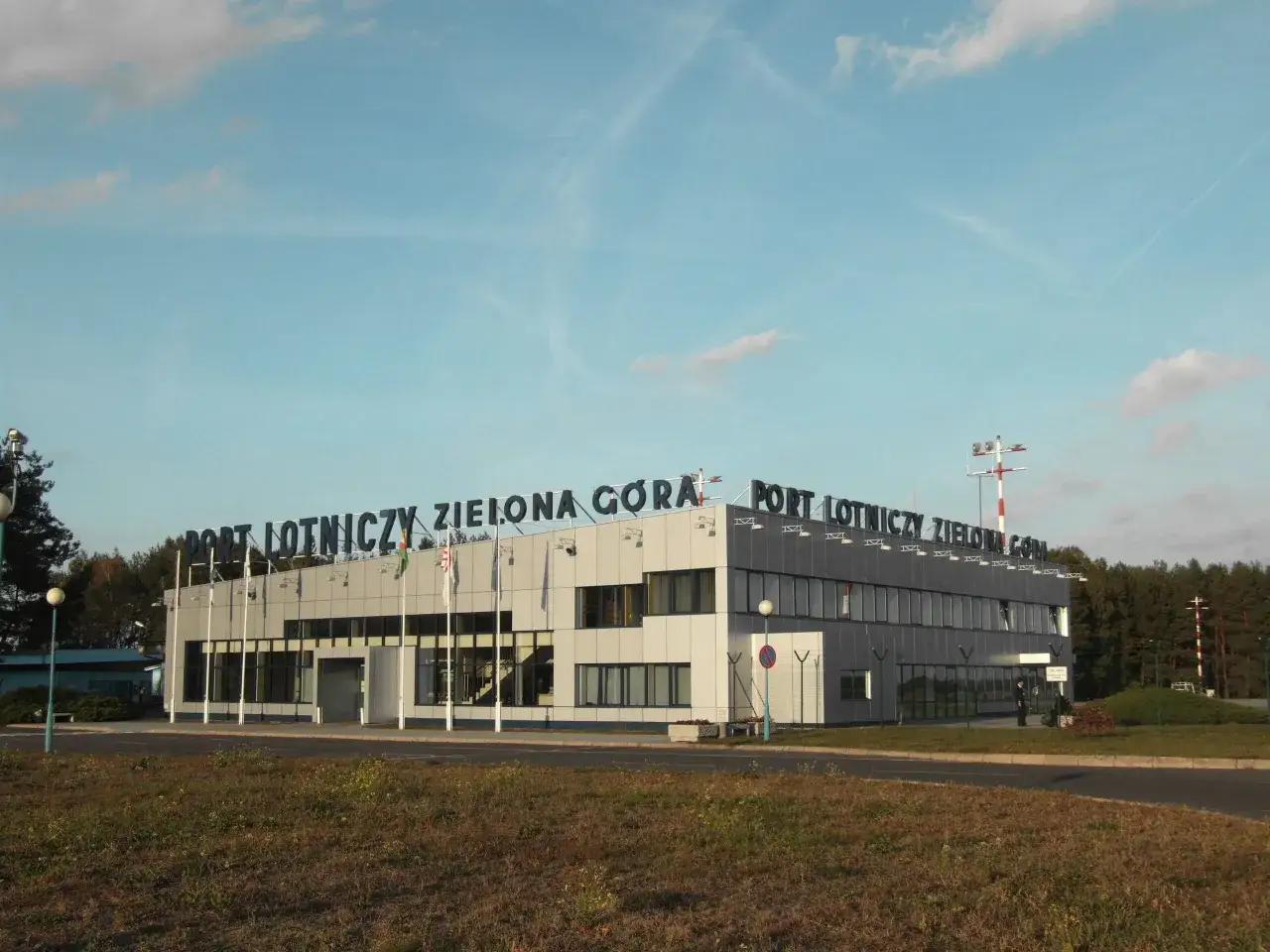 Port Lotniczy Zielona Góra Babimost. Budynek terminala lotniska z napisem na dachu.