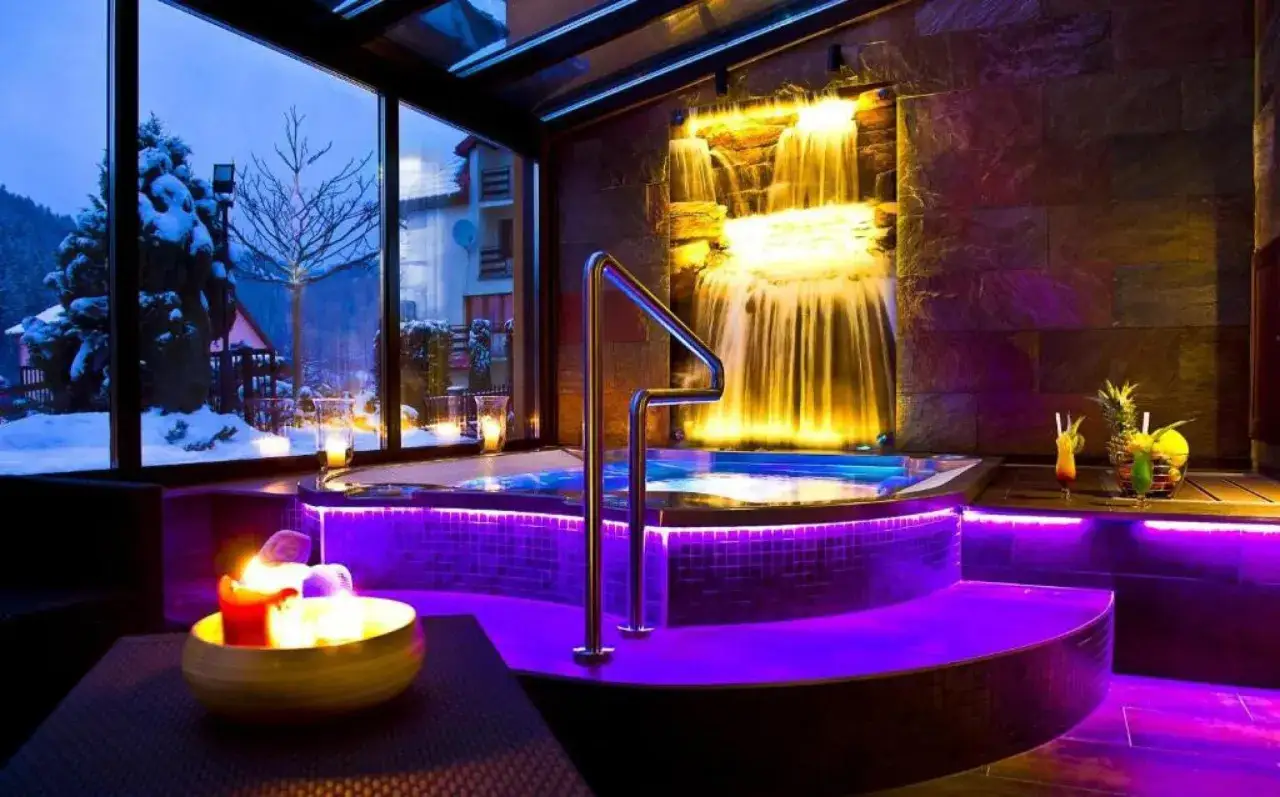 Idealny weekend w spa dla dwojga: jacuzzi z wodospadem, świece i drinki. Za oknem zimowy krajobraz.