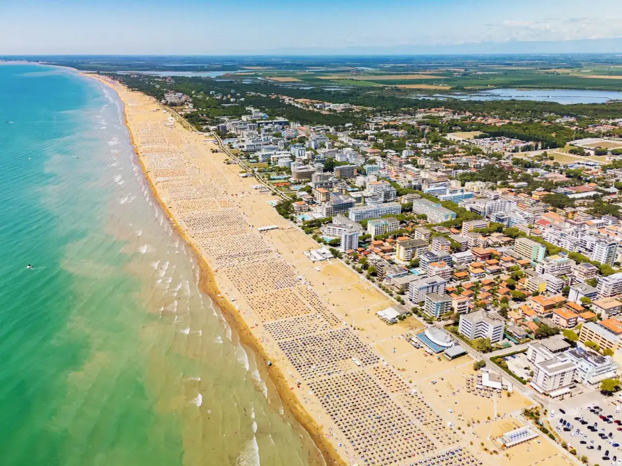 Słoneczna bibione plaża tętni życiem. Tysiące leżaków i parasoli tworzą barwny dywan, a turkusowe morze zaprasza do kąpieli.
