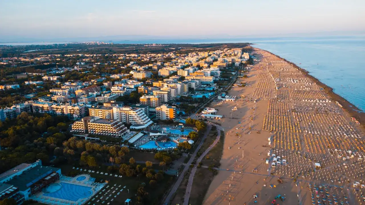 Widok z lotu ptaka na Bibione plażę z rzędami parasoli i hoteli.