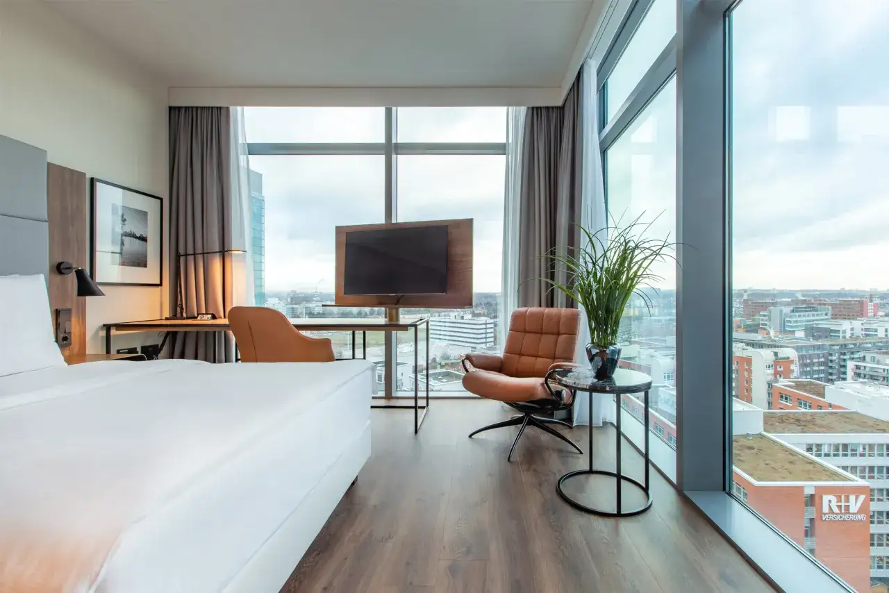 Pokój w hotelu Frankfurt Radisson Blu z widokiem na miasto, łóżkiem, fotelem i biurkiem.
