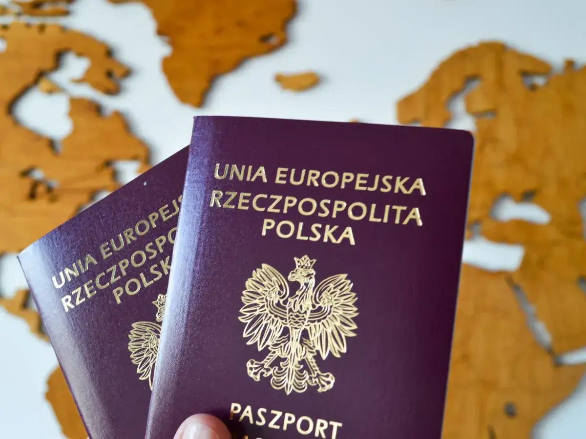 Dwa polskie paszporty na tle mapy świata. Planujesz podróż i zastanawiasz się nad koszt paszportu?
