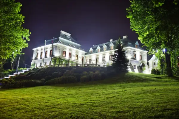 Elegancki pałac nocą, oświetlony blaskiem lamp, otoczony zielenią. Idealne miejsce na romantyczny wypad, jak w najlepszych hotelach dla dorosłych.