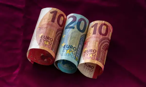 Dwa banknoty 10 euro i jeden 20 euro leżą na bordowym materiale. Łotwa waluta euro.