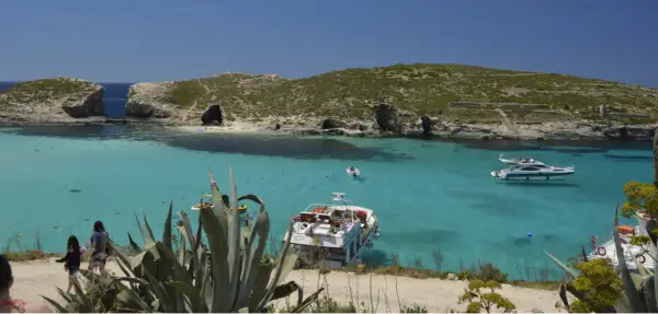 Malta wycieczki: turkusowa woda, łodzie i skaliste wybrzeże. Idealne miejsce na wakacje.