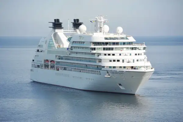 Biały statek wycieczkowy Seabourn Quest płynie po spokojnym, błękitnym morzu.