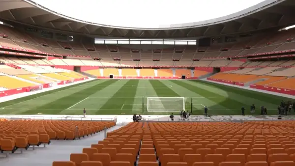 Pusta trybuna stadionu La Cartuja z pomarańczowymi siedzeniami i zieloną murawą.