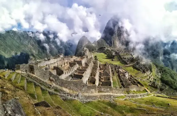 Niesamowita wycieczka do Machu Picchu. Ruiny Inków w chmurach, otoczone zielonymi tarasami i stromymi górami.