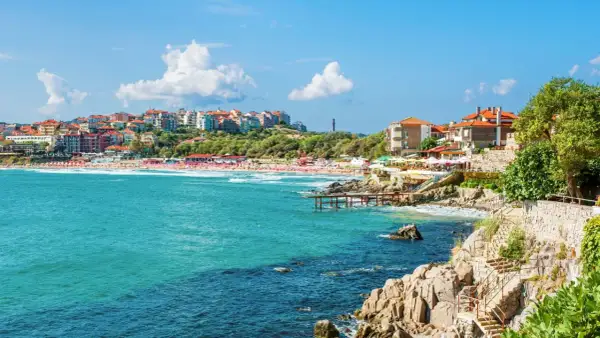 Słoneczne bułgaria plaże z turkusową wodą, kolorowymi budynkami na wzgórzu i kamiennymi schodami prowadzącymi do morza.