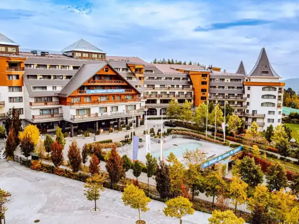 Hotel Gołębiewski w jesiennej odsłonie. Widać jego rozległą architekturę i otoczenie pełne kolorowych drzew.